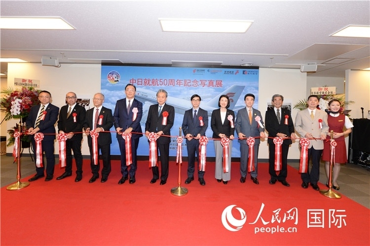 與會(huì)嘉賓共同為中日通航50周年紀(jì)念圖片展開幕剪彩。馮學(xué)敏攝