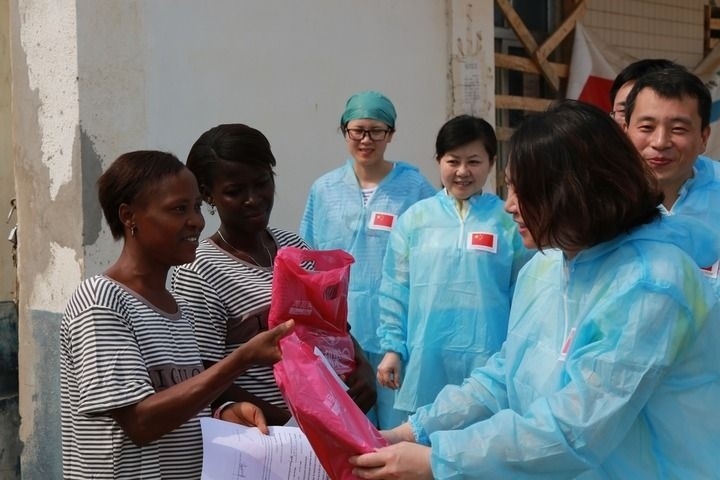 2015年4月4日，在位于塞拉利昂首都弗里敦市郊的中塞友好醫(yī)院埃博拉診療中心，中國第四批援塞醫(yī)療隊(duì)副隊(duì)長(zhǎng)邵蔚（右前）向被治愈的埃博拉出血熱患者贈(zèng)送禮物。新華社發(fā)（祖榮強(qiáng) 攝）
