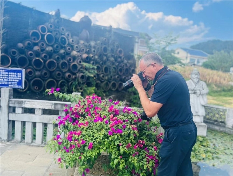 遠(yuǎn)處黔北民居錯(cuò)落有致，近處一只黑色的蝴蝶穿梭于粉紫色三角梅花叢間隙，與俄羅斯“大歐亞”總編輯弗拉基米爾·別列日內(nèi)赫的鏡頭玩起了捉迷藏，“你追我逃，不亦樂乎”。（張亞欣攝）