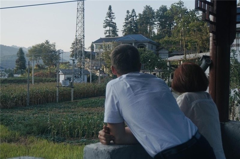 望得見山，看得見水，記得住鄉(xiāng)愁。每個(gè)人心中都有一個(gè)屬于自己的“花茂村”，在這方心田，走遍千山萬水，鄉(xiāng)音未改鬢毛衰。吉爾吉斯斯坦《比什凱克晚報(bào)》第一副總編輯妮娜·尼奇博洛娃與《中國(guó)與俄羅斯》雜志社社長(zhǎng)奧列格·別列日內(nèi)赫攝在花茂村民居屋檐下并肩佇立，眺望山水，尋覓鄉(xiāng)愁。（李光裕攝）