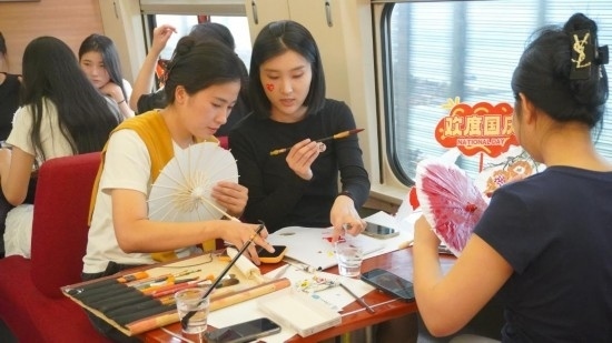 10月1日，旅客們在G1634次列車上給油紙傘作畫。新華社記者周義 攝