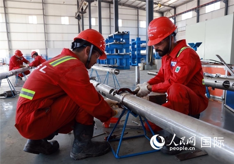 中伊員工共同在檢修鉆井設(shè)備。人民網(wǎng)記者管克江攝