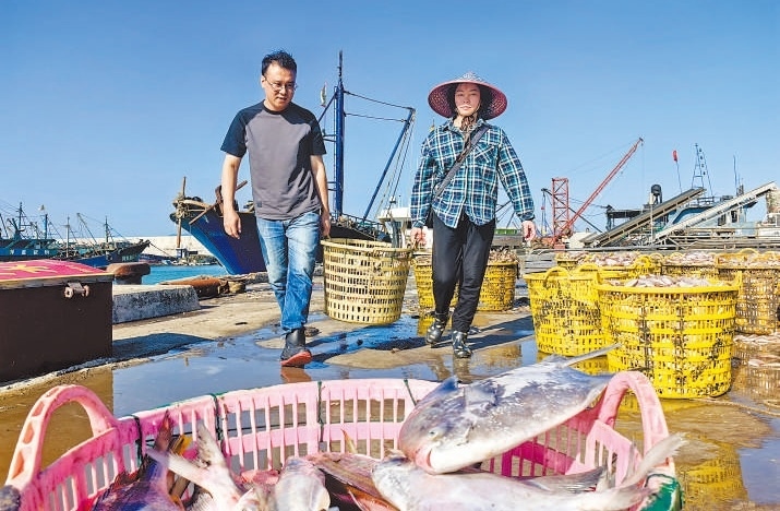 許小斌（左）和漁民一起搬運海鮮。本報記者 付 文攝