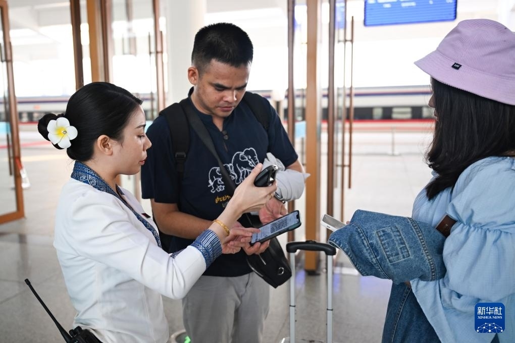 10月12日，在老撾萬象中老鐵路萬象站，工作人員檢驗(yàn)乘客車票。新華社記者 程一恒 攝