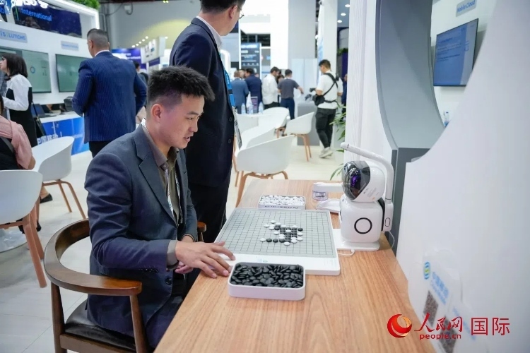 觀眾在中國移動國際有限公司展臺體驗智慧圍棋機器人。人民網 塔里克·易卜拉欣攝