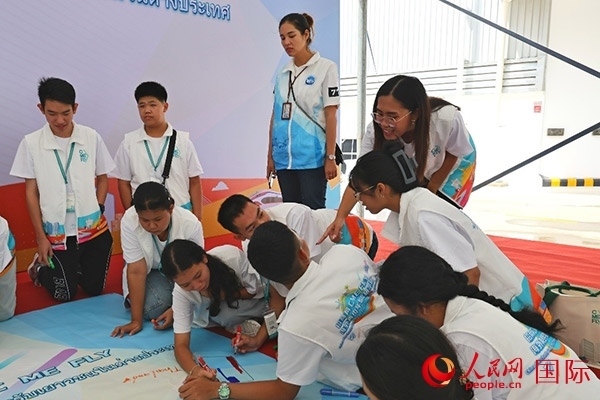 泰國學生在開營儀式展板上繪制圖案。人民網(wǎng)記者 白元琪攝