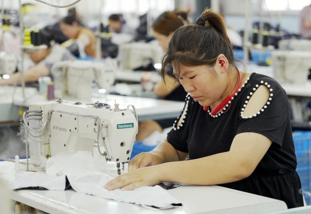 5月20日，村民在李寨村服裝加工廠內(nèi)忙碌。河南省周口市沈丘縣馮營(yíng)鎮(zhèn)李寨村地處豫東平原。近年來，乘著脫貧攻堅(jiān)與鄉(xiāng)村振興政策的東風(fēng)，李寨村積極探索產(chǎn)業(yè)發(fā)展模式，通過“龍頭企業(yè)+村集體經(jīng)濟(jì)+農(nóng)戶”的方式，逐漸發(fā)展形成肉牛養(yǎng)殖、設(shè)施農(nóng)業(yè)、服裝加工、康養(yǎng)民宿等產(chǎn)業(yè)，以產(chǎn)業(yè)振興助力鄉(xiāng)村振興。新華社記者 李嘉南 攝