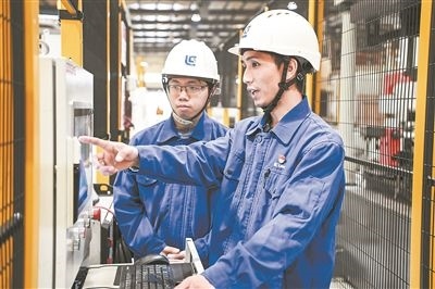 在廣西柳工機械股份有限公司生產(chǎn)車間內(nèi)，一名高級技師（右）給徒弟講解數(shù)控設(shè)備操作細節(jié)。新華社記者 曹祎銘攝