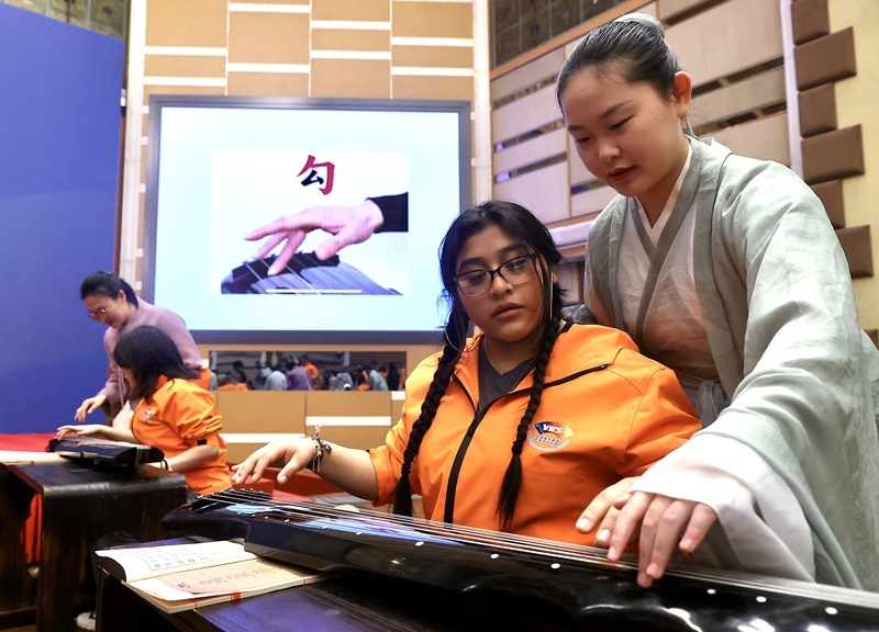 2024年3月20日，美國(guó)華盛頓州中學(xué)生代表團(tuán)北京大學(xué)交流活動(dòng)在北京大學(xué)英杰交流中心舉行。圖為來自華盛頓州的中學(xué)生體驗(yàn)古琴。