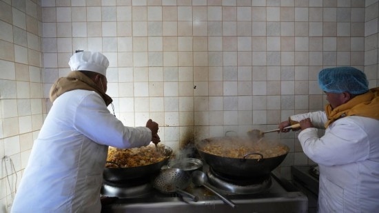 1月14日，服務(wù)隊(duì)的兩名廚師正在為村民們做午飯。新華社記者 邱星翔 攝