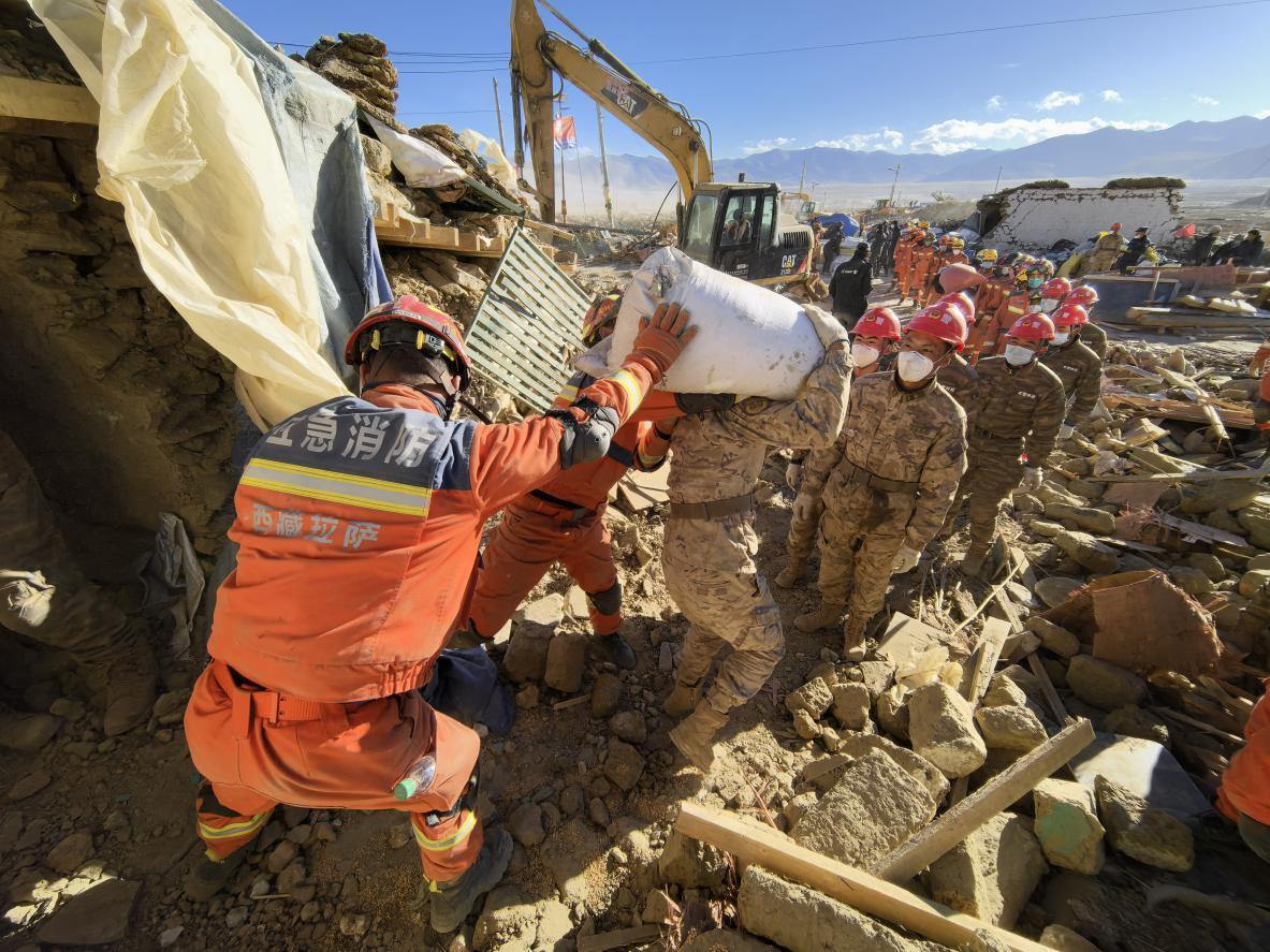 1月11日，定日縣長(zhǎng)所鄉(xiāng)古榮村，應(yīng)急消防等救援人員排隊(duì)接力搶運(yùn)掩埋在倒塌房屋下的群眾財(cái)物。人民日?qǐng)?bào)記者楊翹楚攝