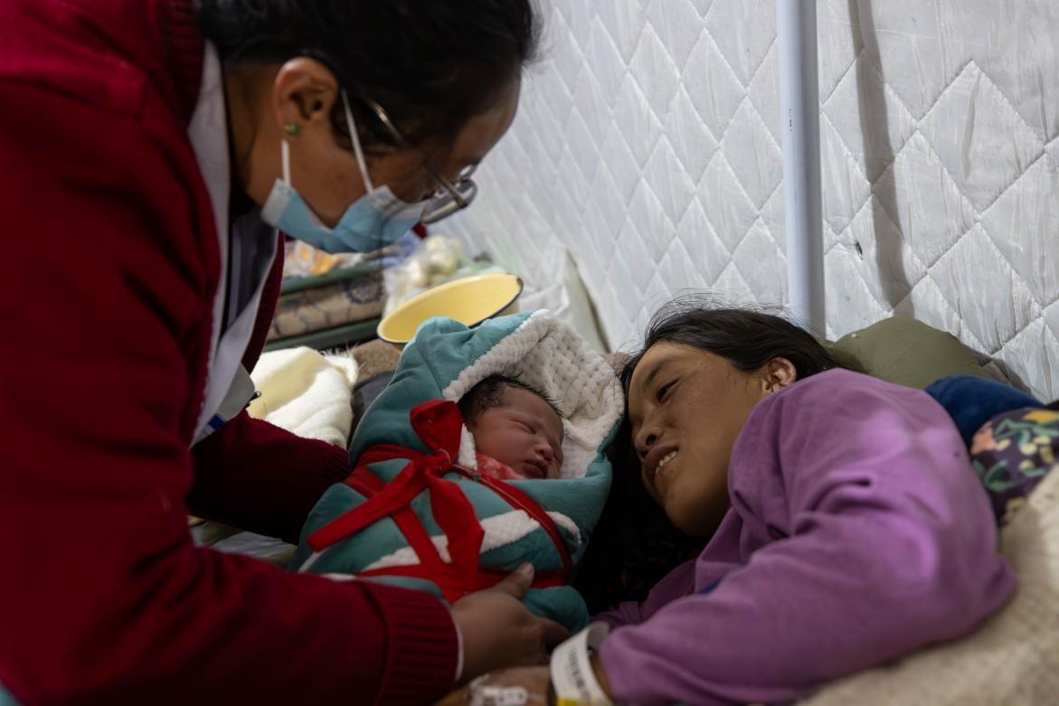 1月10日，定日縣中心醫(yī)院的婦產(chǎn)科醫(yī)生悉心照看一位母親和她懷里的新生兒。人民日?qǐng)?bào)記者張武軍攝