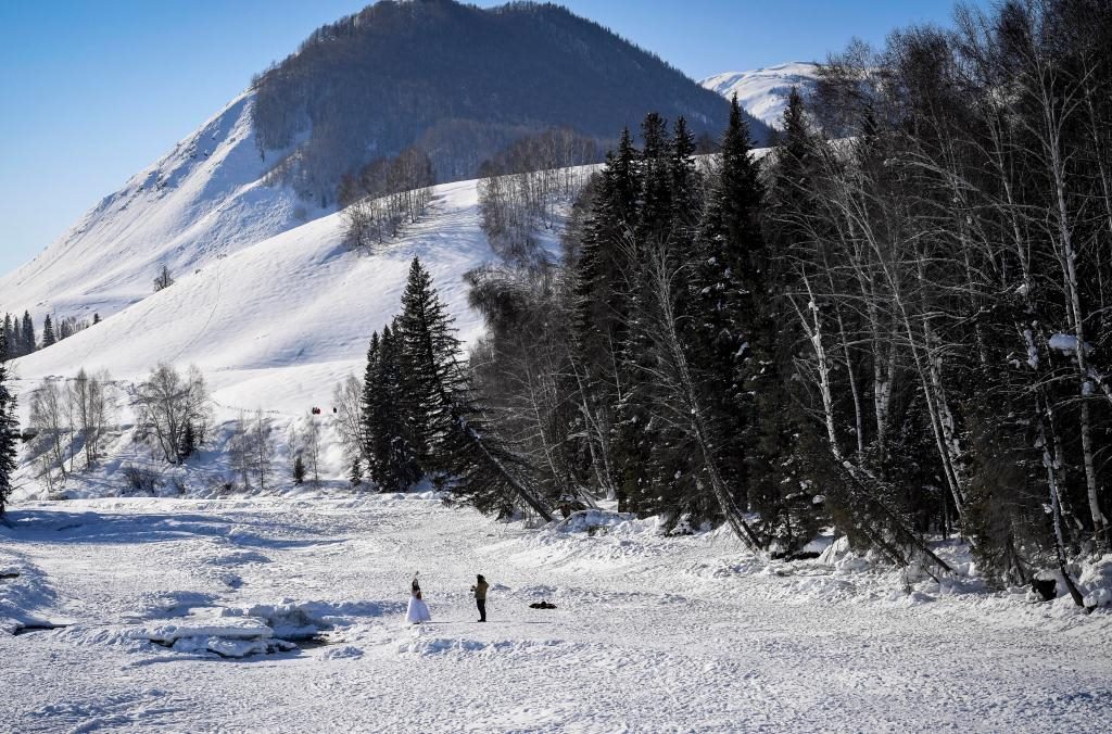 2024年2月5日，兩名游客在新疆阿勒泰地區(qū)布爾津縣禾木村拍照。新華社記者 馬鍇 攝
