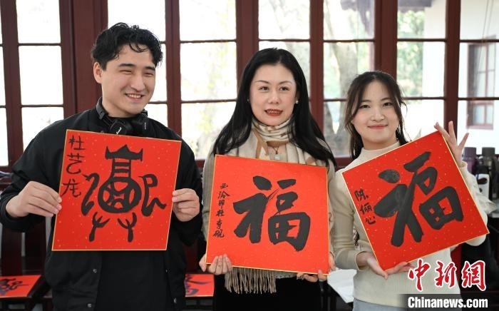 1月20日，外籍留學(xué)生和西泠印社社員李硯(中)展示各自創(chuàng)作的福貼。當(dāng)日，來自巴西、馬來西亞、加納、哈薩克斯坦的外籍留學(xué)生在浙江杭州西泠印社體驗(yàn)福貼、春聯(lián)和篆刻，感受古老的中國傳統(tǒng)文化。中新社記者 王剛 攝