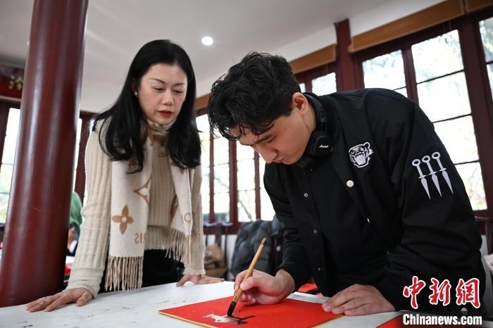 1月20日，外籍留學(xué)生在西泠印社社員李硯指導(dǎo)下寫福。當(dāng)日，來自巴西、馬來西亞、加納、哈薩克斯坦的外籍留學(xué)生在浙江杭州西泠印社體驗(yàn)福貼、春聯(lián)和篆刻，感受古老的中國傳統(tǒng)文化。中新社記者 王剛 攝