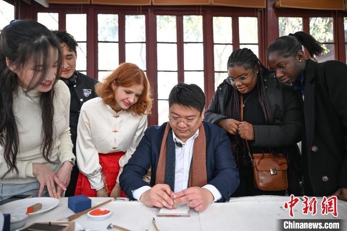 1月20日，篆刻家王臻向外籍留學(xué)生展示篆刻印章。當(dāng)日，來自巴西、馬來西亞、加納、哈薩克斯坦的外籍留學(xué)生在浙江杭州西泠印社體驗(yàn)福貼、春聯(lián)和篆刻，感受古老的中國傳統(tǒng)文化。中新社記者 王剛 攝