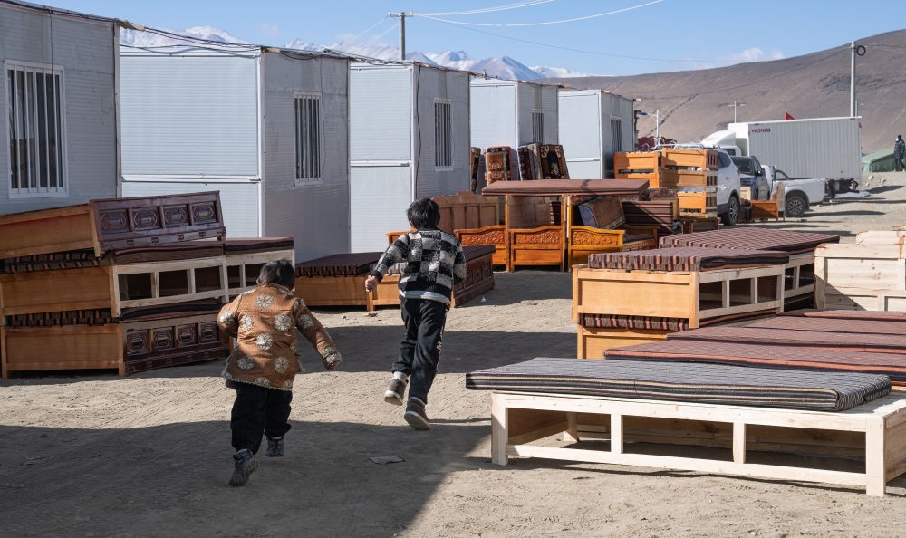 2025年1月13日，在定日縣嘎旦村，兩個(gè)孩子在剛運(yùn)來(lái)的兩排藏床間奔跑。新華社記者丁增尼達(dá) 攝