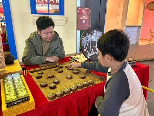 柯秋楓與市民下椰雕象棋。人民網(wǎng) 陳葉欣攝