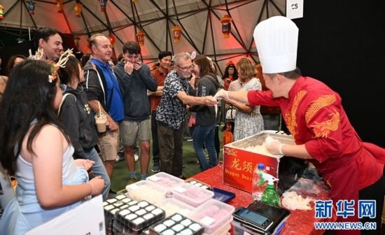 圖為游客在燈節(jié)現(xiàn)場購買小吃。（圖片由奧克蘭中國文化中心提供）