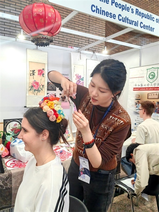 展覽正值羅馬尼亞迎春花節(jié)，國際中文教師志愿者潘婧穎向游客們介紹了國家非物質文化遺產——福建泉州的簪花文化。布加勒斯特大學孔子學院供圖。