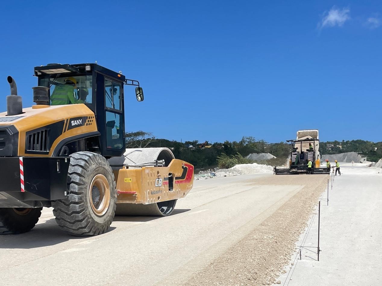 圖為中企承建的牙買加蒙特哥貝繞城路項(xiàng)目基層試驗(yàn)段正在進(jìn)行攤鋪和碾壓施工，相關(guān)施工工作已于日前順利完成。中國港灣美洲區(qū)域公司供圖