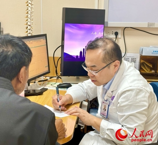 路桂軍接診時(shí)為患者寫下用藥提示。人民網(wǎng)記者 金慧慧攝