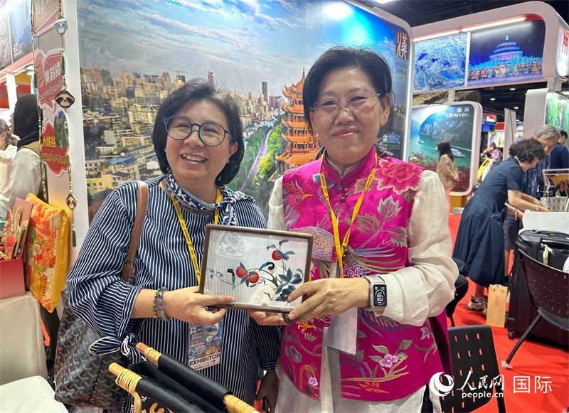 中國“大冶刺繡”傳承人劉小紅（右）參加泰國國際旅游展，向觀眾介紹中國非遺刺繡針法。人民網(wǎng)記者 簡承淵攝