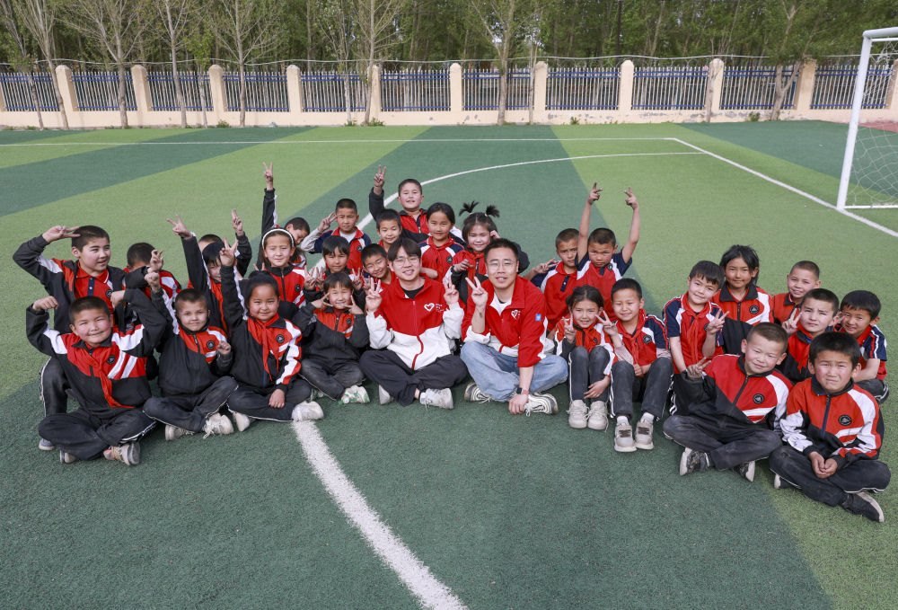 4月23日，在新疆克州阿圖什市哈拉峻鄉(xiāng)謝依特小學(xué)，支教教師王俊文（中左）、李軻凡（中右）和學(xué)生在一起。