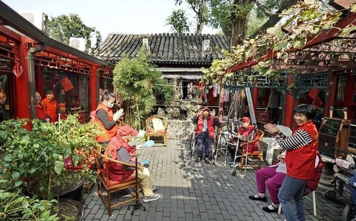 2024年10月12日，鐘樓灣胡同的老年人在社區(qū)內(nèi)的四合院養(yǎng)老驛站休閑。2017年起，北京市先后開展了兩輪背街小巷環(huán)境整治提升行動，完整保留了中軸線生活建筑群的歷史信息，并根據(jù)居民的生活和居住方式進(jìn)行適配化的更新和改造，極大地改善了生活環(huán)境。2023年鐘樓灣胡同被評為“北京最美街巷”。