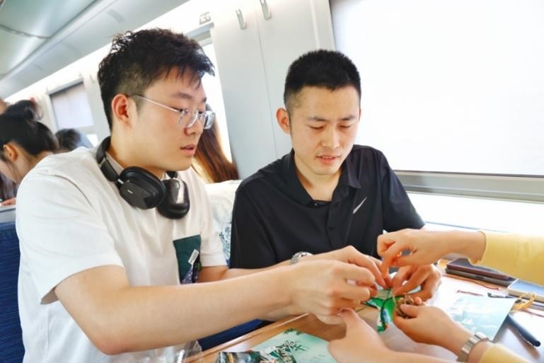 G232次旅客親手制作端午荷包和五彩繩。王磊攝