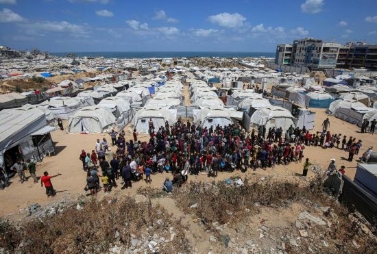 5月28日，人們?cè)诩由吵俏鞑康纳程犭y民營(yíng)等待領(lǐng)取救助食物。新華社發(fā)（里澤克·阿卜杜勒賈瓦德攝）