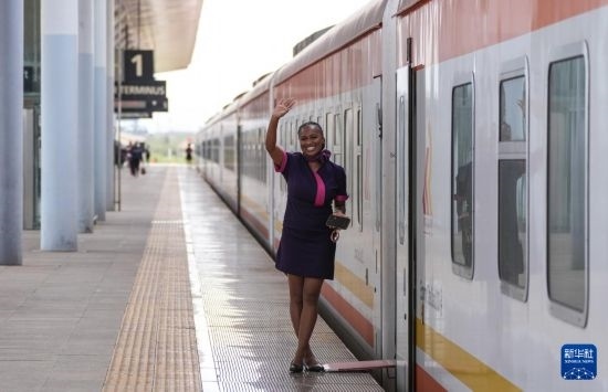 5月31日，在蒙內(nèi)鐵路內(nèi)羅畢站，一名乘務(wù)員在即將開往蒙巴薩的E2次列車旁等候乘客。新華社記者 李亞輝 攝